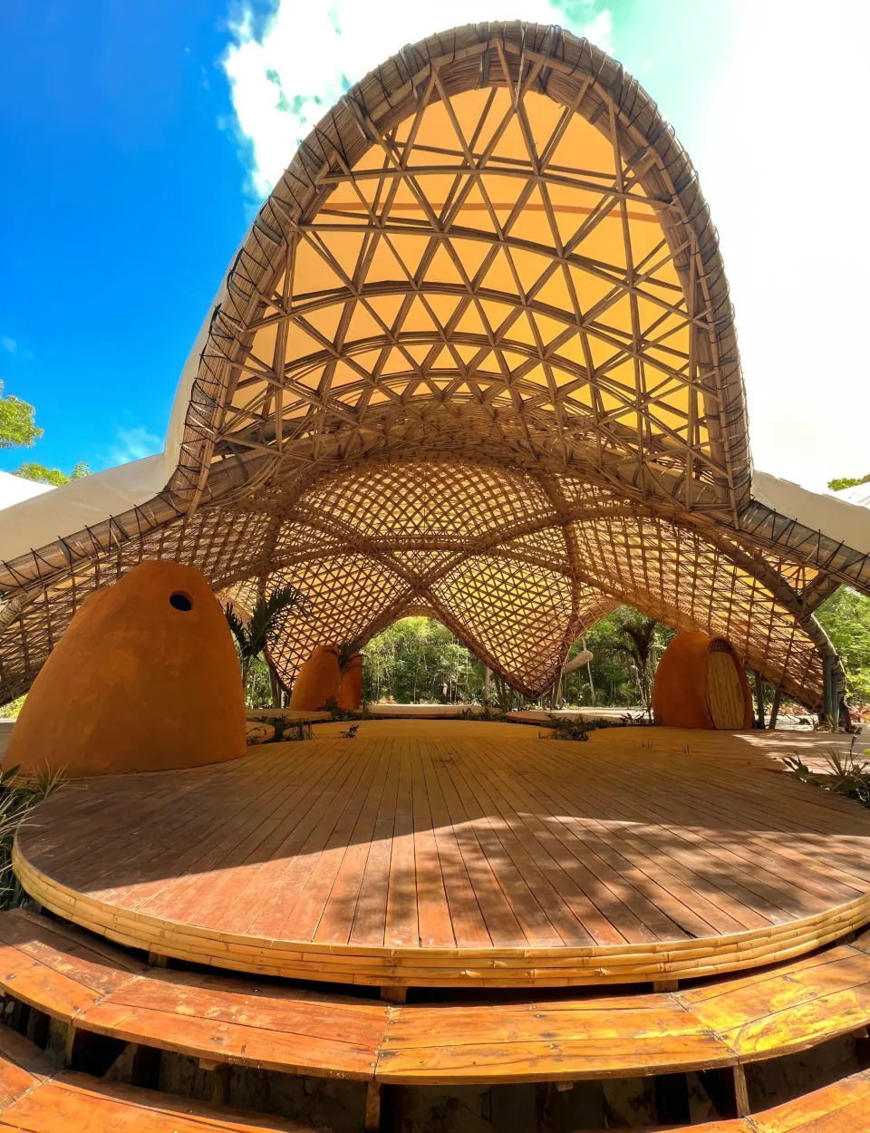 A woven bamboo pavilion with a pointed dome, open to the sky.