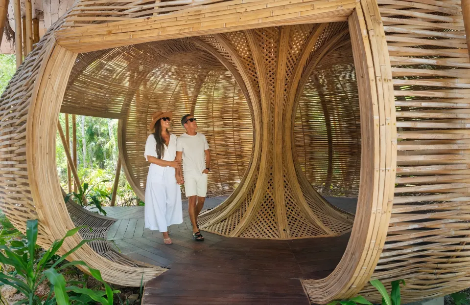 A large woven bamboo pod in the garden with a wooden floor.
