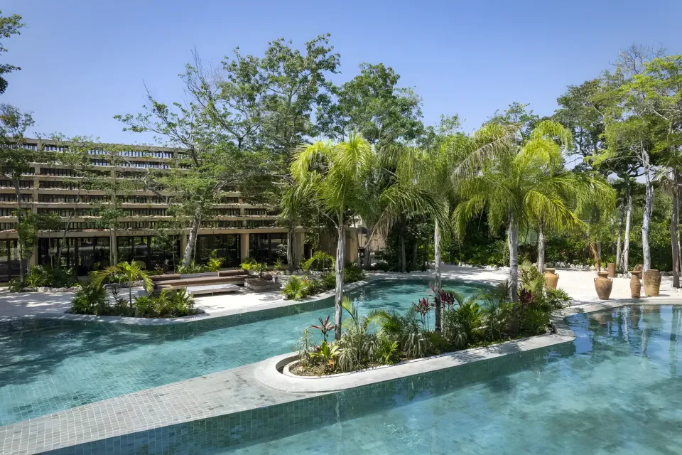 A long turquoise pool winding between palm trees.