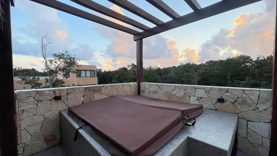 The rooftop jacuzzi under a wooden pergola at golden hour.