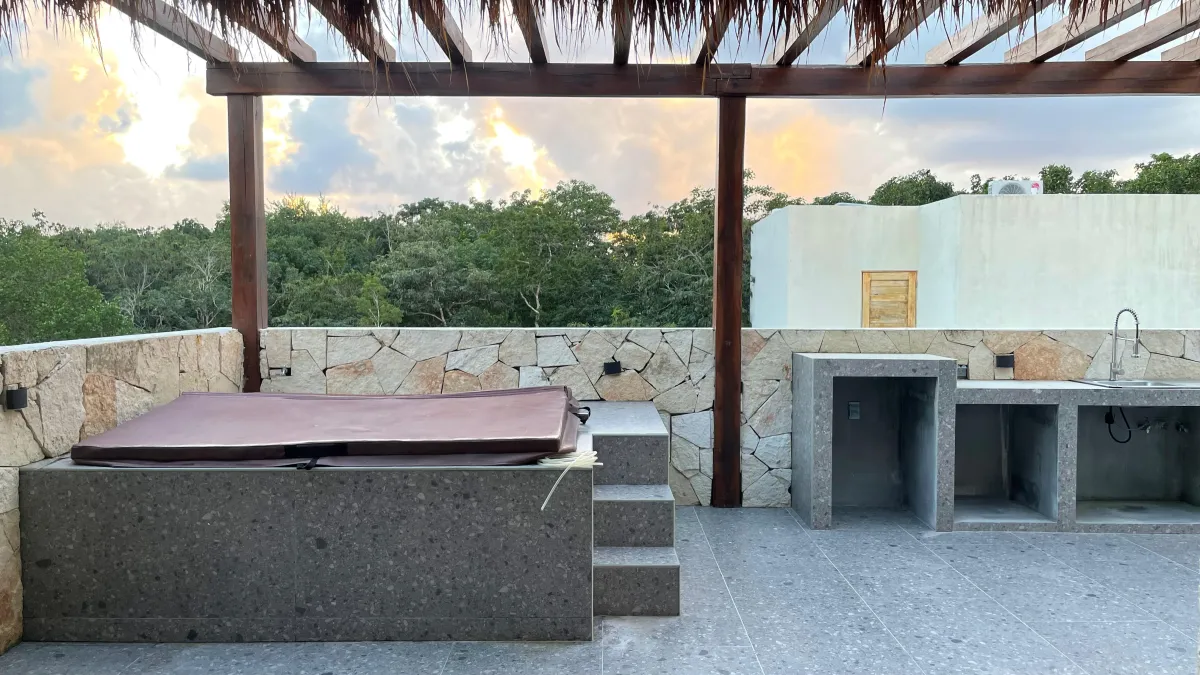 The villa's rooftop at sunset, with a pergola, a jacuzzi and the jungle all around.